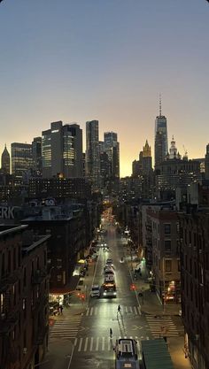 the city skyline is lit up at night, with cars driving down the street in the foreground