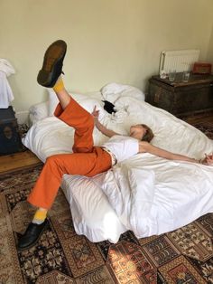 a woman laying on top of a bed with her feet up in the air next to a black cat