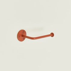 an orange metal hook on a white wall