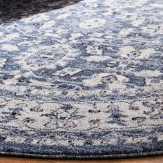 a blue and white area rug on a wooden floor with a black chair in the background