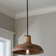 a wooden light fixture hanging from a ceiling in a room with white walls and windows