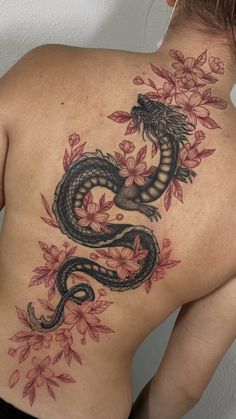 the back of a woman's body with a dragon tattoo on her left side