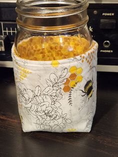 a jar filled with honey sitting on top of a wooden table next to a microwave