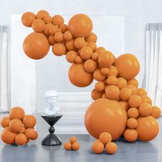 an orange balloon sculpture is in front of a white wall and some black vases