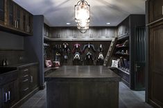 a walk in closet filled with lots of coats and shoes on shelves next to a sink