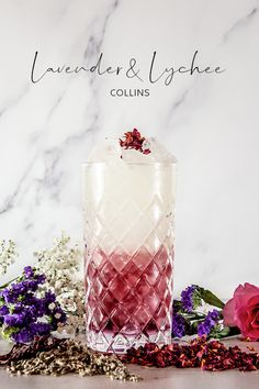 a pink and white drink sitting on top of a table next to some purple flowers