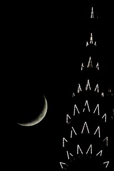 a clock tower with the moon in the sky above it and a crescent on top