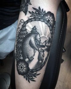 a black and white photo of a bear in a circle with flowers on it's arm