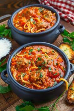 two blue pots filled with meatballs and pasta on top of a wooden cutting board