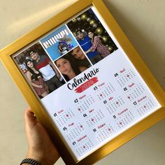 a person holding up a framed calendar with photos on it