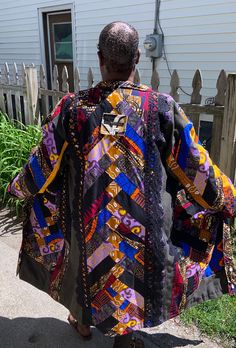 a man is walking down the street wearing a colorful coat and skateboard in his hand