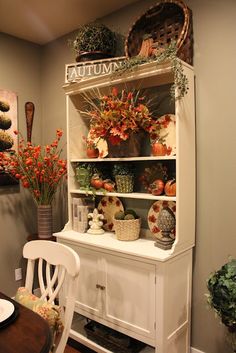 a white china cabinet with autumn decorations on top