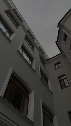 an apartment building with many windows and shutters on the side, against a cloudy sky