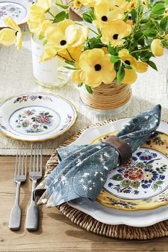 the table is set with yellow flowers and plates