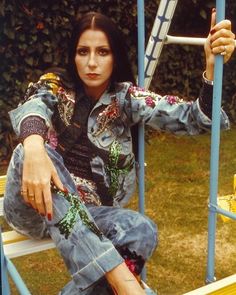 a woman sitting on top of a blue metal structure holding a baseball bat in her hand