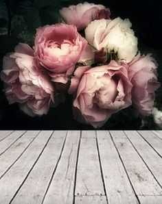 some pink flowers are on top of a wooden floor and there is no image here