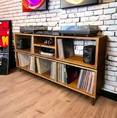 an entertainment center with various records and audio equipment on display in front of a brick wall