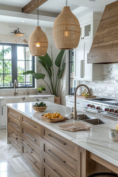 a large kitchen with two hanging lights above the island and fruit bowls on the counter