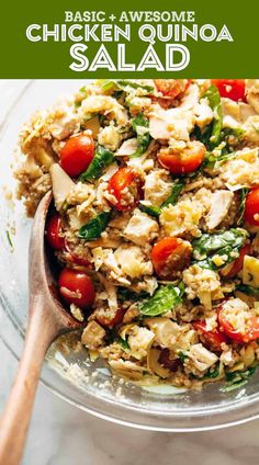 chicken and quinoa salad in a glass bowl with a wooden spoon on the side