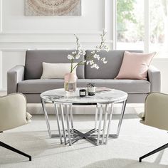 a living room with a gray couch and white table in the middle, surrounded by chairs