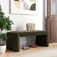 a green bench sitting on top of a wooden floor next to a potted plant