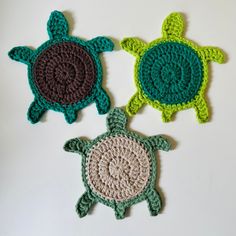 three crocheted turtle coasters on a white surface