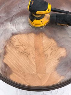 a yellow and black sanding machine on top of a round table with wood planks