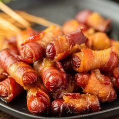 bacon wrapped in strips on a black plate with chopsticks next to the dish