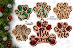 wooden cutout christmas ornaments with the word dog and paw prints on them, surrounded by evergreen branches