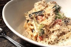 a white bowl filled with pasta and veggies on top of a marble counter