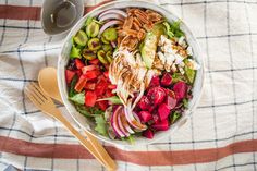 a white bowl filled with salad next to a cup of coffee on top of a checkered table cloth