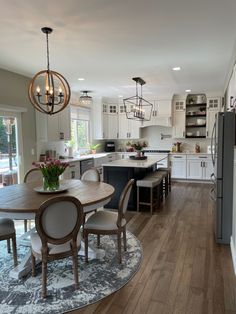 a kitchen and dining room with wood floors, white cabinets and an oval rug on the floor