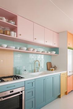 a kitchen with pastel colored cabinets and white counter tops is pictured in this image