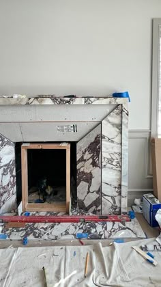 an unfinished fireplace in the middle of a room with construction materials on the floor and walls