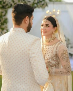 a bride and groom standing next to each other in front of a decorated area with flowers