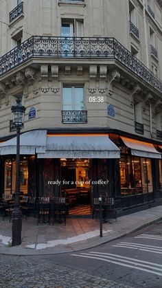 the corner of a building with an awning and tables on the sidewalk in front of it