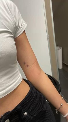 a woman's left arm with a tiny star tattoo on the right side of her stomach