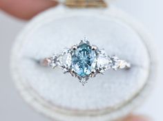 a blue diamond ring is being held by someone's hand