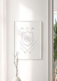 a white vase sitting on top of a wooden table next to a framed logo above it