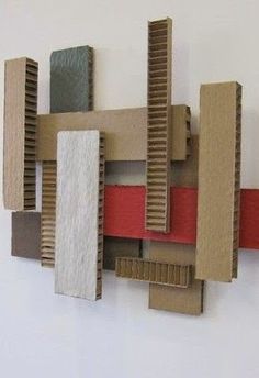 a wall sculpture made out of cardboard and colored paper on a white wall with a red strip in the middle