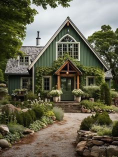 a green house with lots of plants and trees on the front yard, along with stone steps leading up to it