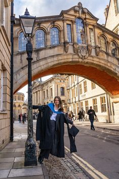 a woman is standing under an arch in the street with her coat draped over her shoulders