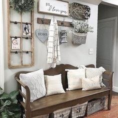 a wooden bench sitting in front of a wall filled with pillows and baskets on top of it