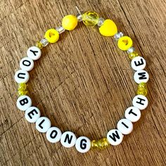 a yellow and white beaded bracelet with words that say you belong, be strong