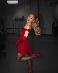 a woman in a red dress and high heels posing with her legs spread out to the side