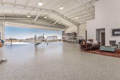 an airplane is parked in the middle of a large room with concrete flooring and white walls