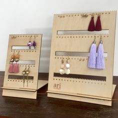 two wooden earrings and earring display stands on a table with wood grained surface