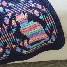 a crocheted blanket sitting on top of a white couch next to a pillow