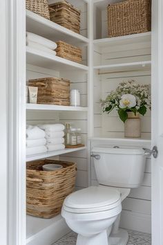 a white toilet sitting inside of a bathroom next to shelves filled with towels and baskets