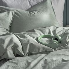 a pair of headphones sitting on top of a bed next to an unmade pillow